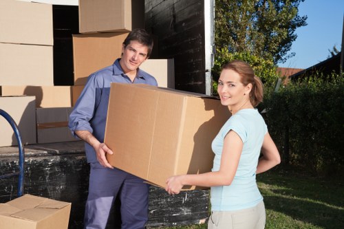 Packed moving boxes and furniture staged for collection by a removal van